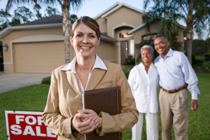Realtor with African American couple in front yard of house for sale